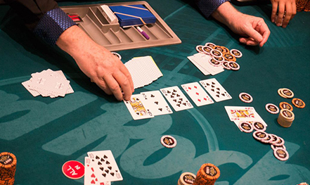 représente une table de poker avec des cartes sur la table et de chaque coté ainsi qu'un poisson bodybuilder sur le coté